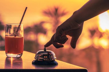 Kadın aşçı, restoranın garsonu içecek hazır mı diye uyarmak için zili çalıyor. Gün batımında brach kafe deniz ve palmiye ağacı manzarası.. 