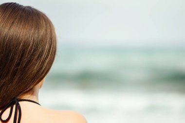 Sahilde tek başına denize bakan bir kadın. Yaz tatilinde kadın dinlenmesi. Arka plan