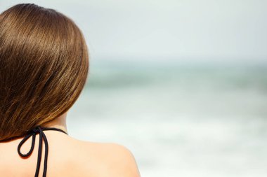 Sahilde tek başına denize bakan bir kadın. Yaz tatilinde kadın dinlenmesi. Arka plan