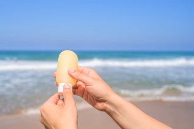 Deniz kıyısındaki bir sahilde el kremi süren bir kadın. Yaz tatilinde kadın dinlenmesi. Arka plan
