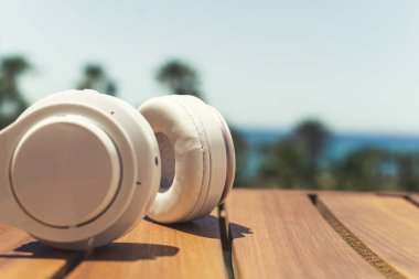 Palmiye ağacı ormanındaki masada kulaklıklar. Yaz tatili. Müziği dinle. Kapatın. Kırpılmış. Kavram