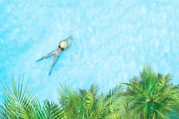 穿着比基尼和草帽的年轻女子的头像是在透明的蓝色大海中 棕榈树下的泻湖中游泳 无人驾驶飞机视图 — 图库照片