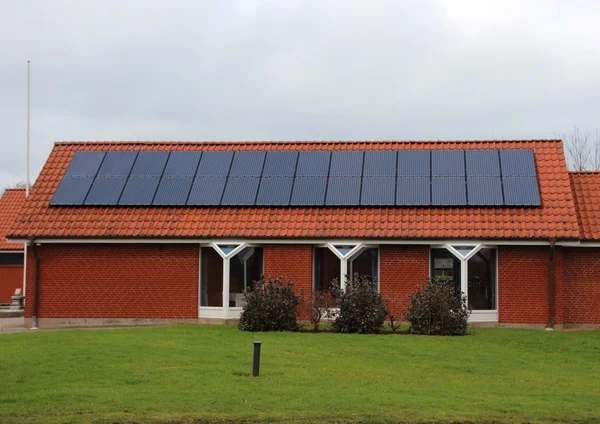 Cella del pannello solare del sole sul tetto della casa rossa — Foto Stock
