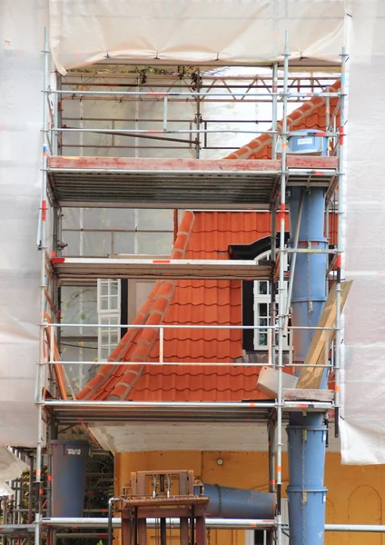 Old house under repair with scaffold and tarpaulin — Stock Photo, Image