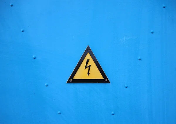 Señal de triángulo de advertencia eléctrica amarilla sobre fondo azul Fotos de stock