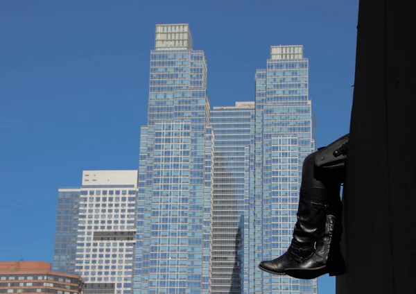 Ruhende schwarze Lederstiefel mit Wolkenkratzer-Hintergrund — Stockfoto