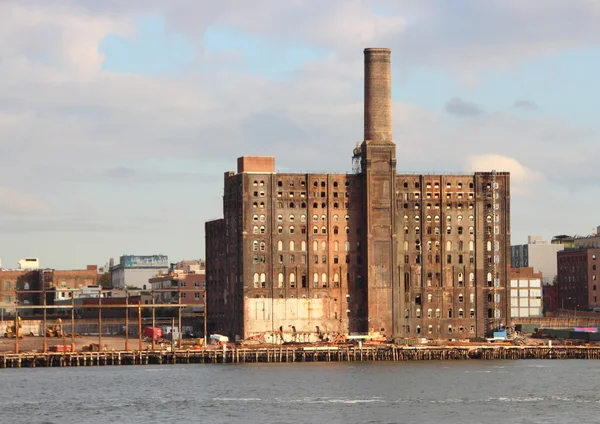 Alte Fabrik an der Seebrücke mit Fluss im Vordergrund aufgeben — Stockfoto