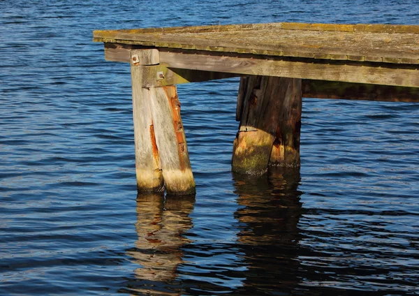Extremo del muelle de madera con reflexión de agua oscura — Foto de Stock