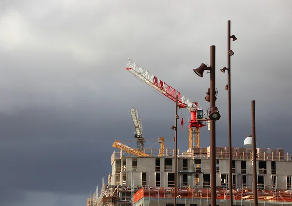 Cranes and Street Lamps at Building Site with Dark Clouds — Stock Photo, Image