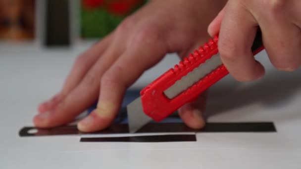 De mensenhanden knippen voorzichtig een kleine magneet uit met een mes. — Stockvideo