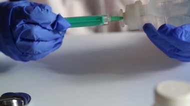 Doktor enjeksiyon için şırıngayı sıvıyla dolduruyor. Eldivenli eller. 