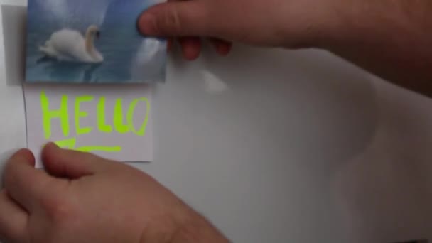 Мужчины руки висят куски бумаги на поверхности холодильника с — стоковое видео