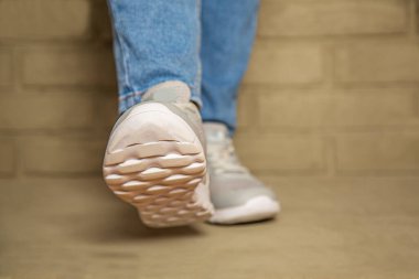 Yolda yürüyen kadın kotu ve spor ayakkabısı. Aşağıdan bak. Taban görünür..