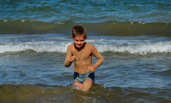 Çocuk denize adım atar. Mutlu bir çocuk denizde yüzüyor. Çocuk denizden deniz kıyısına gider. Yaz. Tatilde. Aileye git..