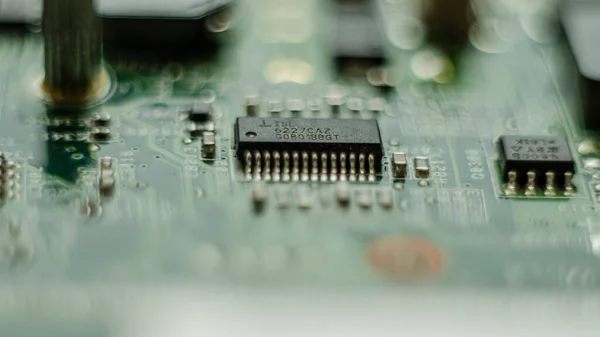 Complex electronics, green circuit board with a microcontroller, microprocessor control chip in the middle, extreme closeup detail macro, technology engineering abstract circuits industrial background
