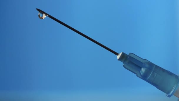 A drop of medicine drips from the needle of a disposable syringe. — Video