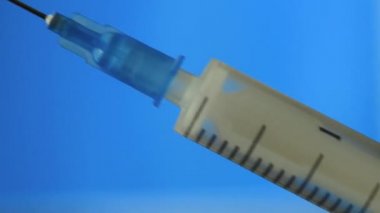 The syringe is filled with medicine on a blue background.