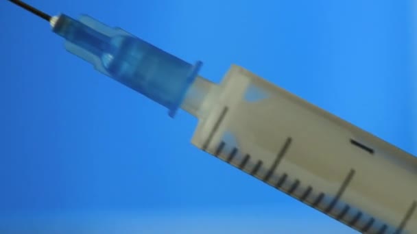 The syringe is filled with medicine on a blue background. — Stock Video