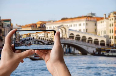 Büyük Kanal 'da Bridge Rialto' nun fotoğrafını çeken bir turist ve İtalya Venedik 'te gondol teknesi.