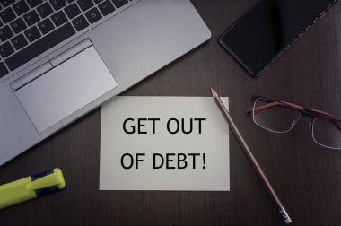 Get out of debt card. Top view of office table desktop background with laptop, phone, glasses and pencil with card with inscription get out of debt. Business concept. clipart