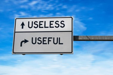 Kullanışsız ve kullanışsız kelimelerle dolu yol işareti. Mavi gökyüzü arka planında metal direkli beyaz iki sokak işareti. 