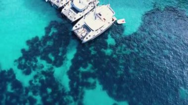 Kristal şeffaf mavi su üzerinde küçük teknelerin yukarıdan aşağı görüntüsü.