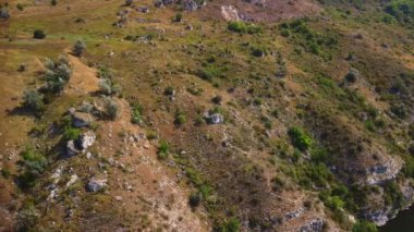 İnsansız hava aracı bir dağ yamacına yaklaşıyor, uçurumlu kayalık bir tepe..