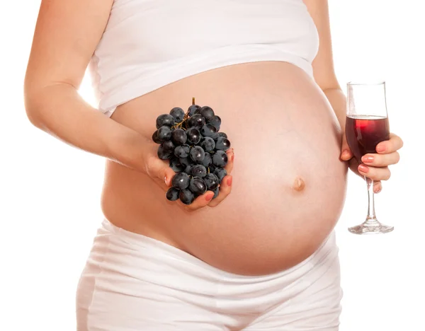Беременная женщина с бокалом вина и гроздью винограда в руке — стоковое фото