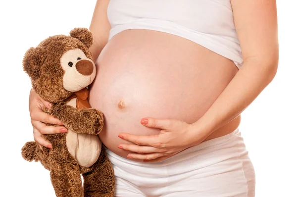 Мама во время беременности держит плюшевого мишку Стоковая Картинка