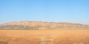 Dasht Arjan 'ın otlakları. Sonbahar çimen tarlası ve akşam vakti arka planda dağlarla geniş bir manzara. Fars Eyaleti, İran 'ın tipik sonbahar manzarası.