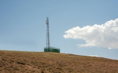 İran Kürdistan 'da radyo kulesi ve mavi bulutlu gökyüzü ile çevrili bir tepe.