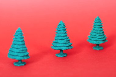 Kırmızı arka planda yeşil plastik Noel ağacı