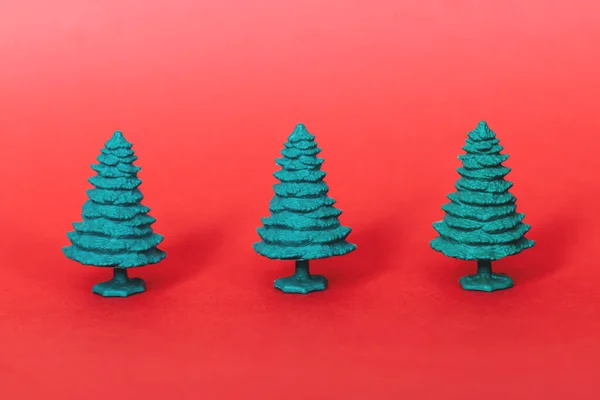 Kırmızı arka planda yeşil plastik Noel ağacı