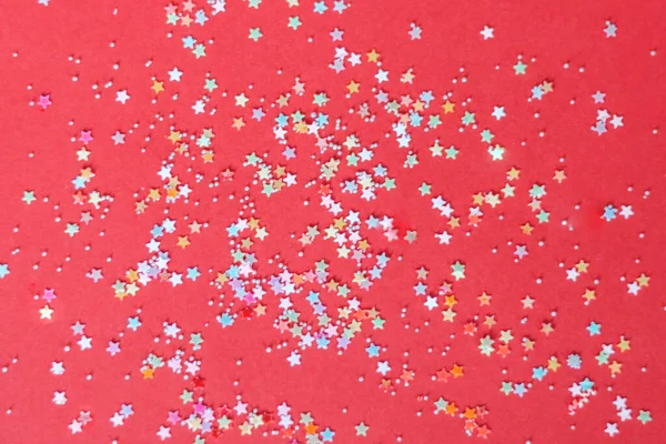 Kırmızı arkaplanda çok renkli ışıltılar.