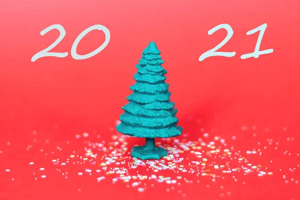 Kırmızı arka planda yeşil plastik Noel ağacı