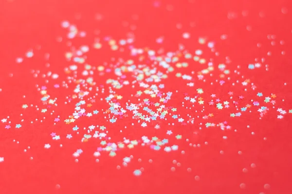 Kırmızı arkaplanda çok renkli ışıltılar.