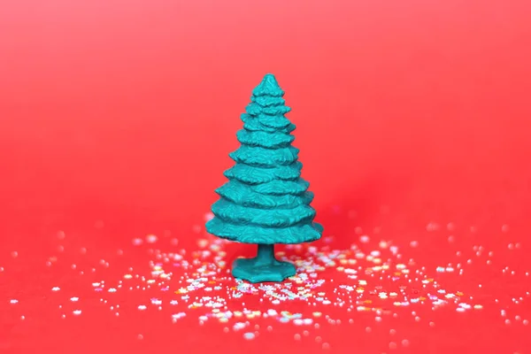 Kırmızı arka planda yeşil plastik Noel ağacı