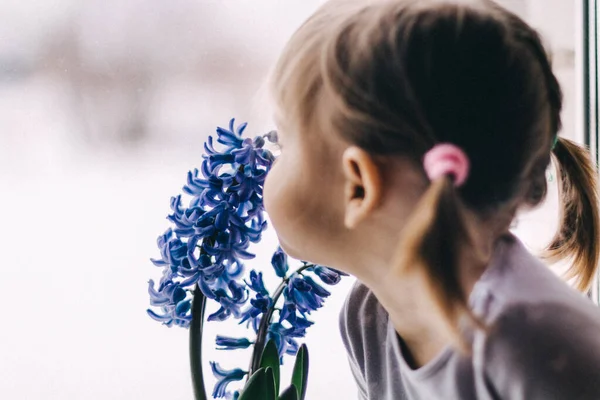 Mavi çiçeğin yanında baharın gelişini bekleyen küçük bir kız..