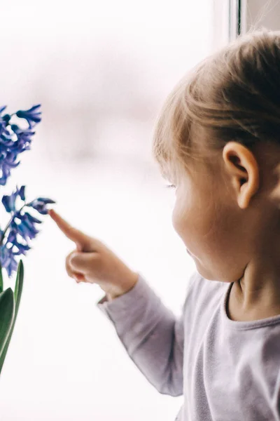 Mavi çiçeğin yanında baharın gelişini bekleyen küçük bir kız..