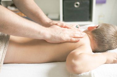 Profesyonel fizyoterapist klinikte bir çocuğu tedavi ediyor. Çocuk terapi masajından sonra rahatlıyor..