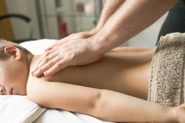 Profesyonel fizyoterapist klinikte bir çocuğu tedavi ediyor. Çocuk terapi masajından sonra rahatlıyor..