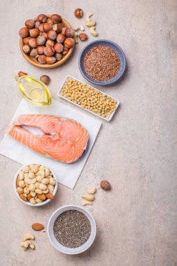 Omega 3 yiyecek kaynakları ve beton arka planda Omega 6, üst görünüm kopyalama alanı. Sebzeler, deniz ürünleri, fındık ve tohumlar da dahil olmak üzere yüksek yağ asitleri içeren yiyecekler