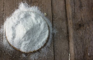 Sıradan tuz. Kaba taneli tuz ahşap arka planda ve saman kasesinde