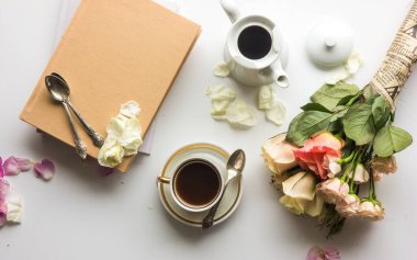 Beyaz arka planda bir fincan kahve ve çiçekler