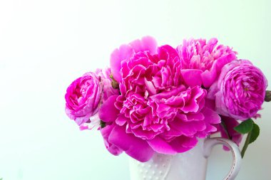 Beyaz arka planda pembe şakayık çiçekleri ve güller