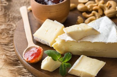 Krem peynirli reçel. Camembert peyniri. Taze Brie peyniri ve tahtadan bir dilim fındık, bal ve yaprakla. İtalyan, Fransız peyniri.