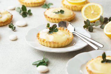 Fransız tatlısı. Limonlu kremalı tartlar. Beton bir masada taze nane ile doldurulmuş.
