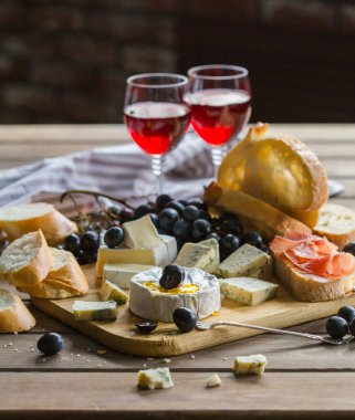 Tahta tahtada çeşitli peynirler. Camembert peyniri, küflü peynir, gouda, sert peynir, çilek, nane yaprağı, peynir için bıçak.