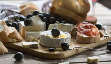 Tahta tahtada çeşitli peynirler. Camembert peyniri, küflü peynir, gouda, sert peynir, çilek, nane yaprağı, peynir için bıçak.