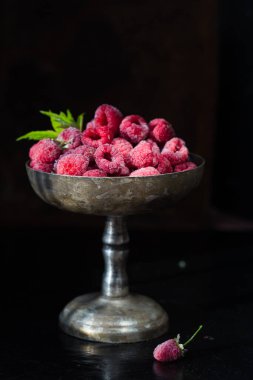Gümüş kasedeki parlak donmuş ahududular hasat ediyor.